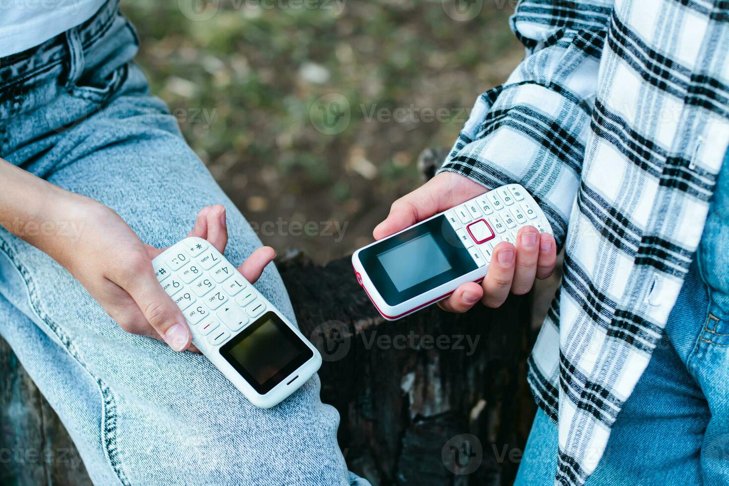 gens dans jeans tenir bouton Téléphone (s dans leur mains sur leur les genoux photo