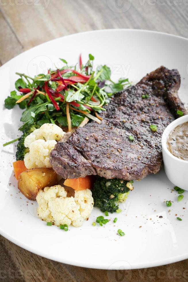 steak de bœuf de qualité supérieure avec légumes cuits à la vapeur et sauce aux champignons repas gastronomique sur plaque blanche photo