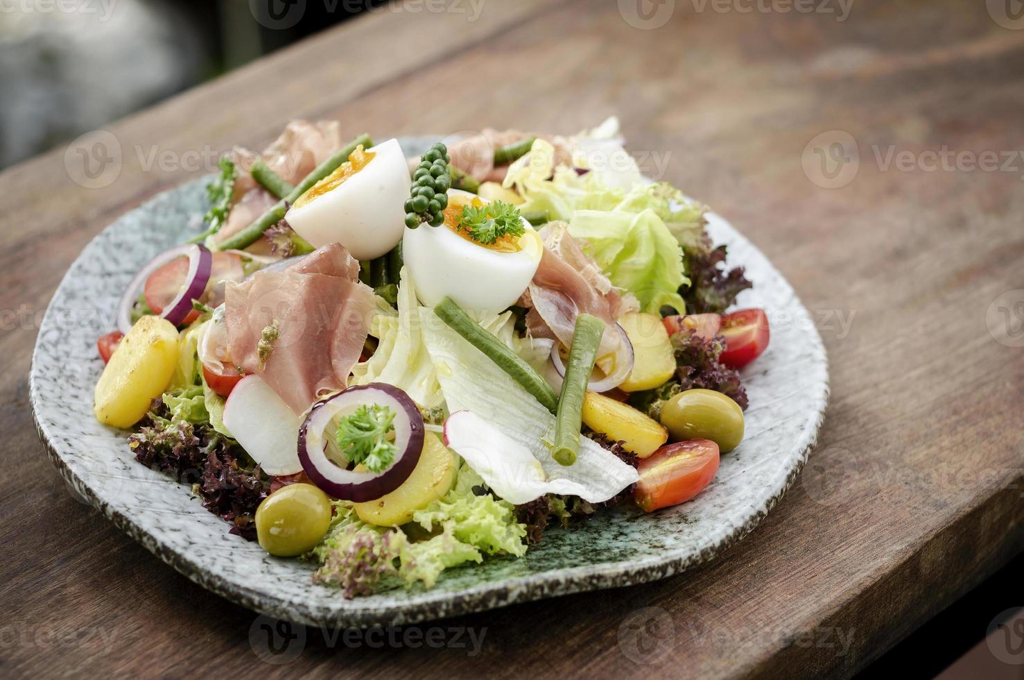 Salade rustique bio saine de style niçois avec oeuf et jambon à l'extérieur photo