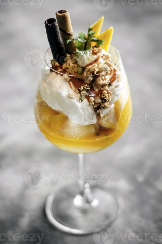 Coupe glacée tropicale à la mangue et aux fruits de la passion biologique dans un verre à vin photo