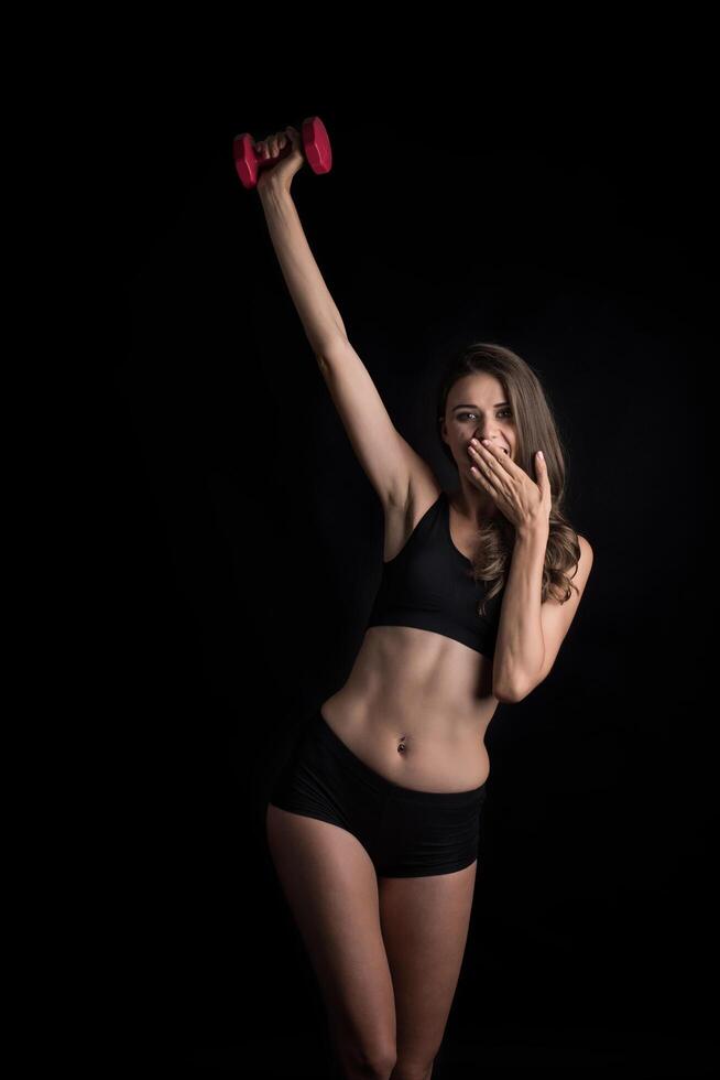 belle jeune femme faisant des exercices physiques avec des haltères. photo