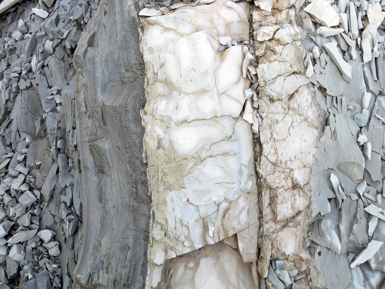 rocher de montagne avec des pierres de couleur grise, blanche et brune en couche verticale photo