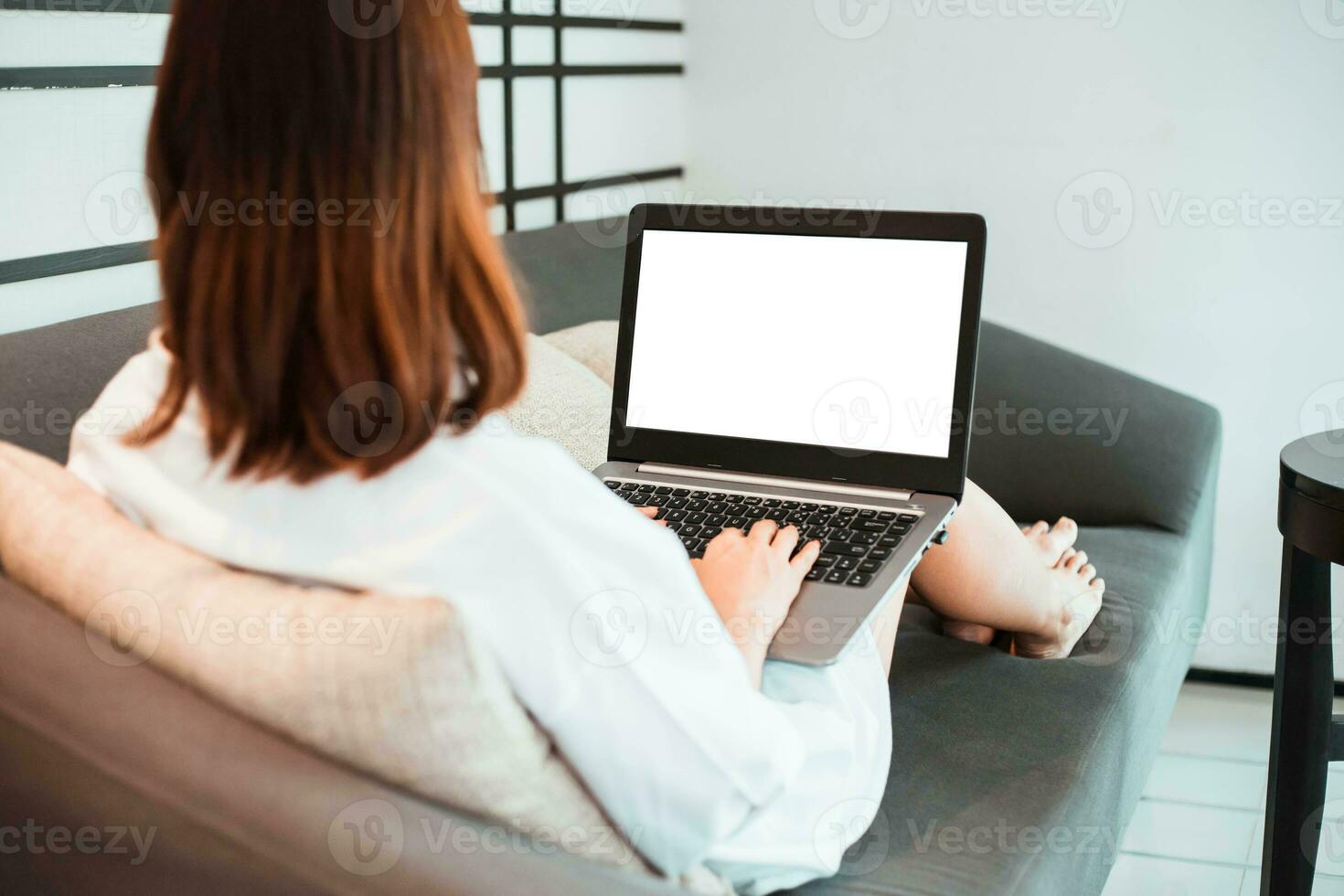 Jeune femme travail sur portable ordinateur tandis que séance à le vivant chambre. travail de Accueil concept photo
