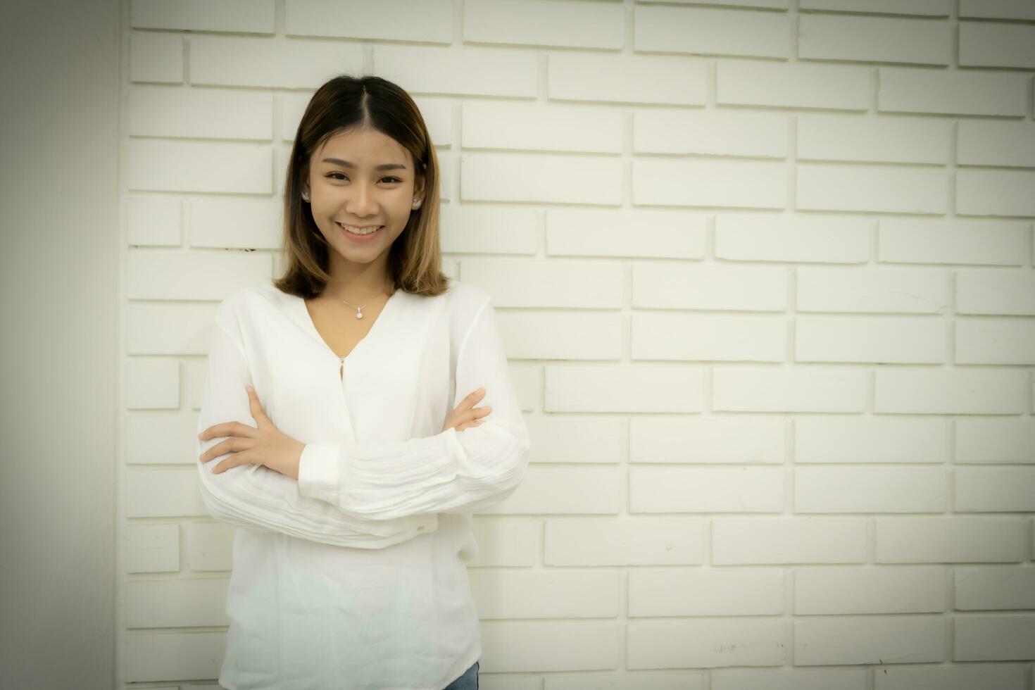 portrait de une magnifique affaires femme est permanent avec bras franchi et à la recherche à le caméra avec sourire sur sa affronter. photo