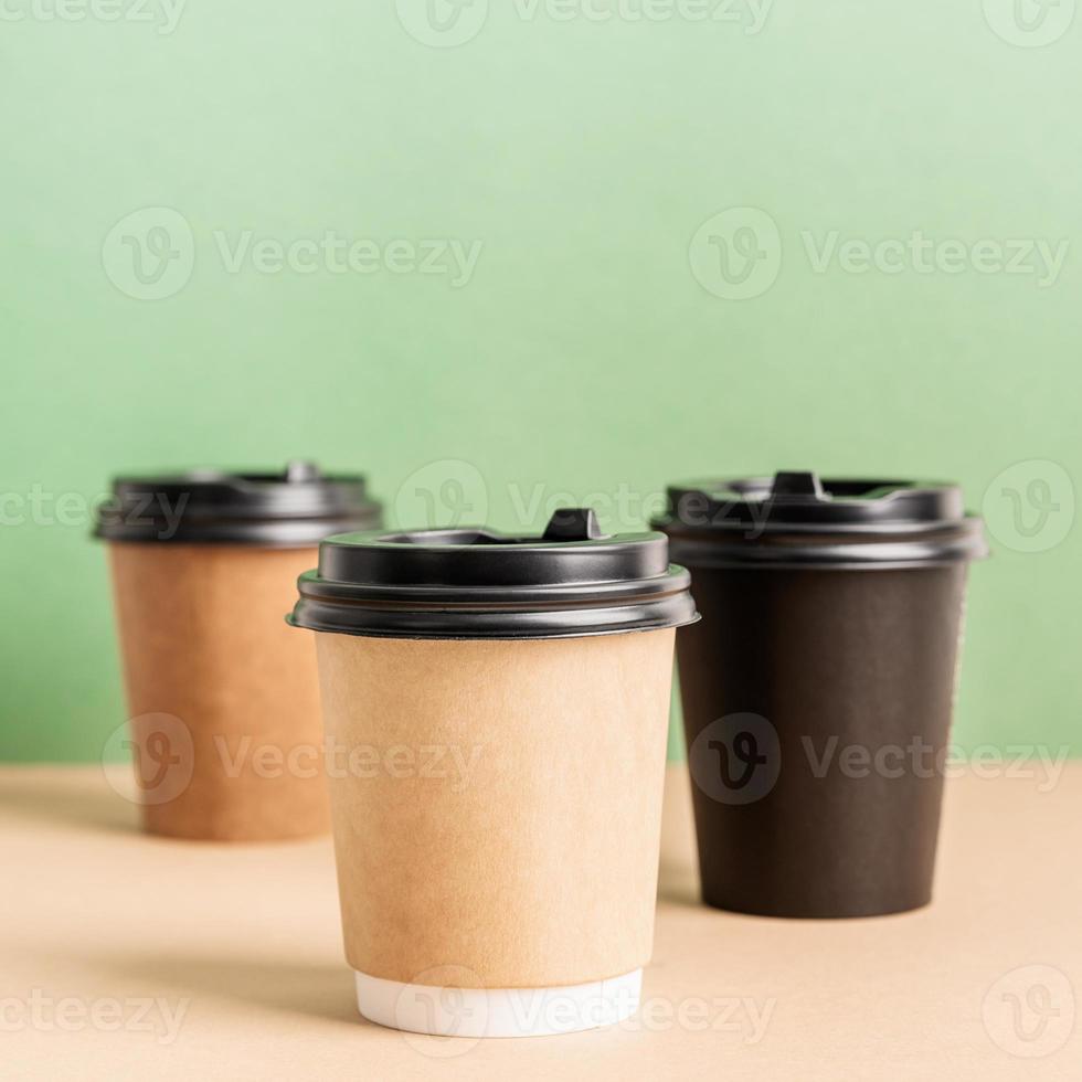 des tasses à café en papier à emporter noir se moquent sur fond vert et marron photo