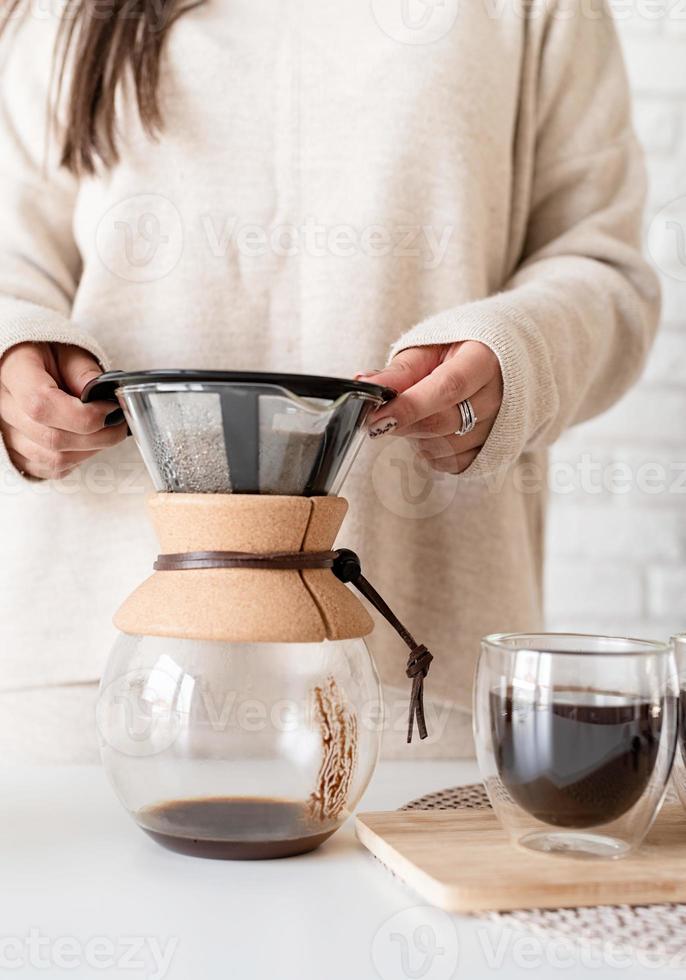 Jeune femme prépare du café dans une cafetière et coupe un gâteau photo