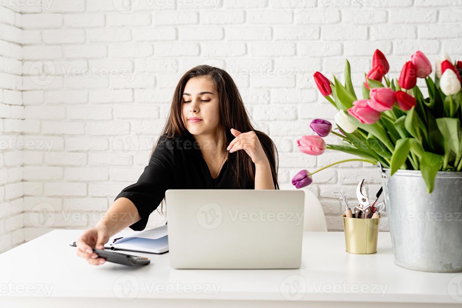 femme d'affaires fleuriste utilisant un ordinateur portable au bureau, calculant les coûts photo