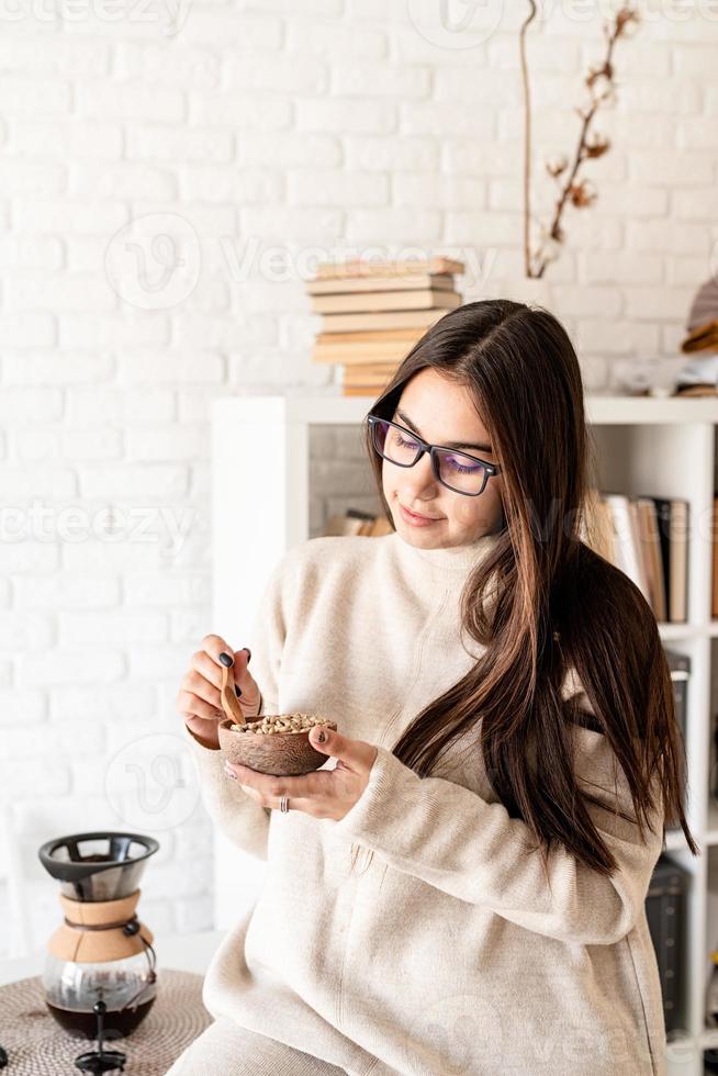 femme prépare du café dans une cafetière, sentant les grains de café verts photo