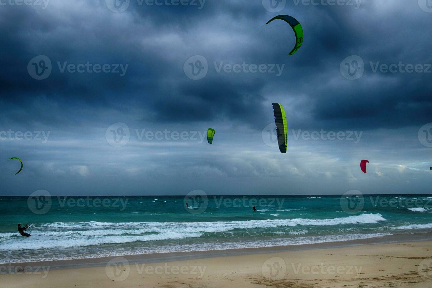 été paysage avec le océan avec foncé nuageux vagues et surfeurmi trousse avec parachutes flottant sur le rive photo