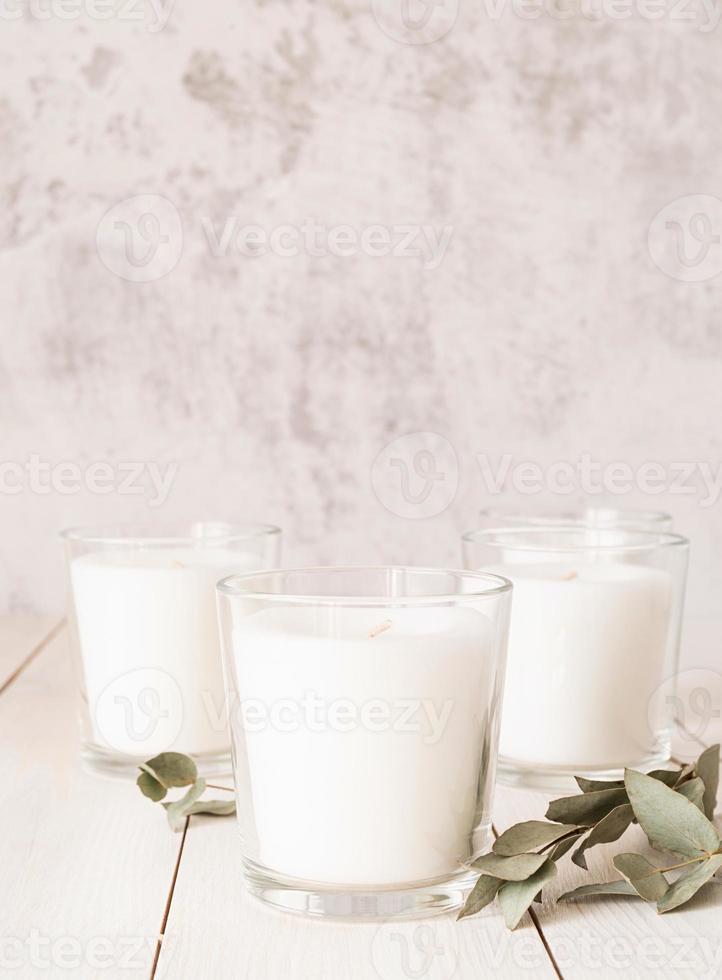 bougies blanches avec des feuilles d'eucalyptus sur fond de bois blanc photo