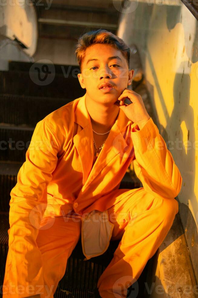 un asiatique homme dans une Jaune costume est séance sur une ascenseur dans une bâtiment photo