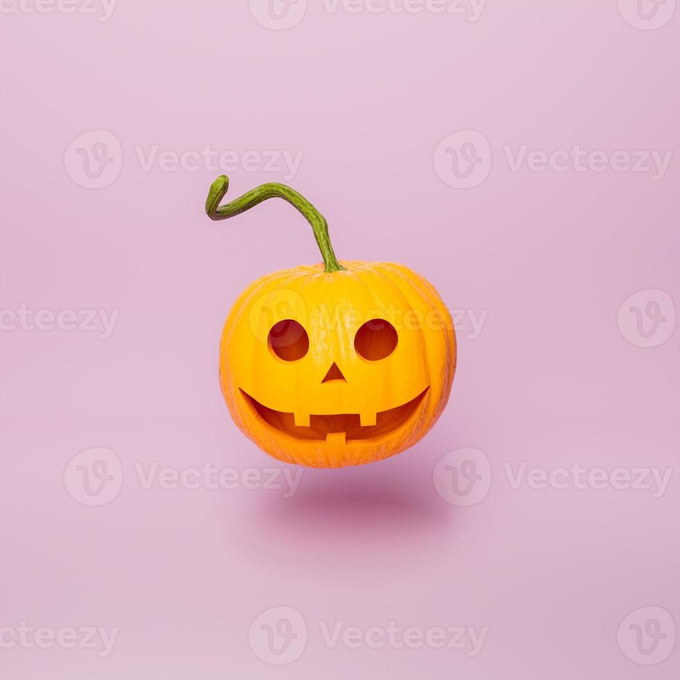 citrouille d'halloween avec un visage heureux sur fond rose minimal photo