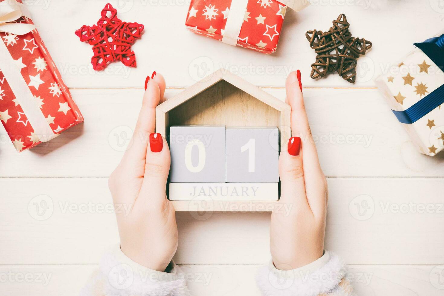 vue de dessus des mains féminines tenant un calendrier sur fond en bois. le premier janvier. décorations de vacances. notion de nouvel an photo