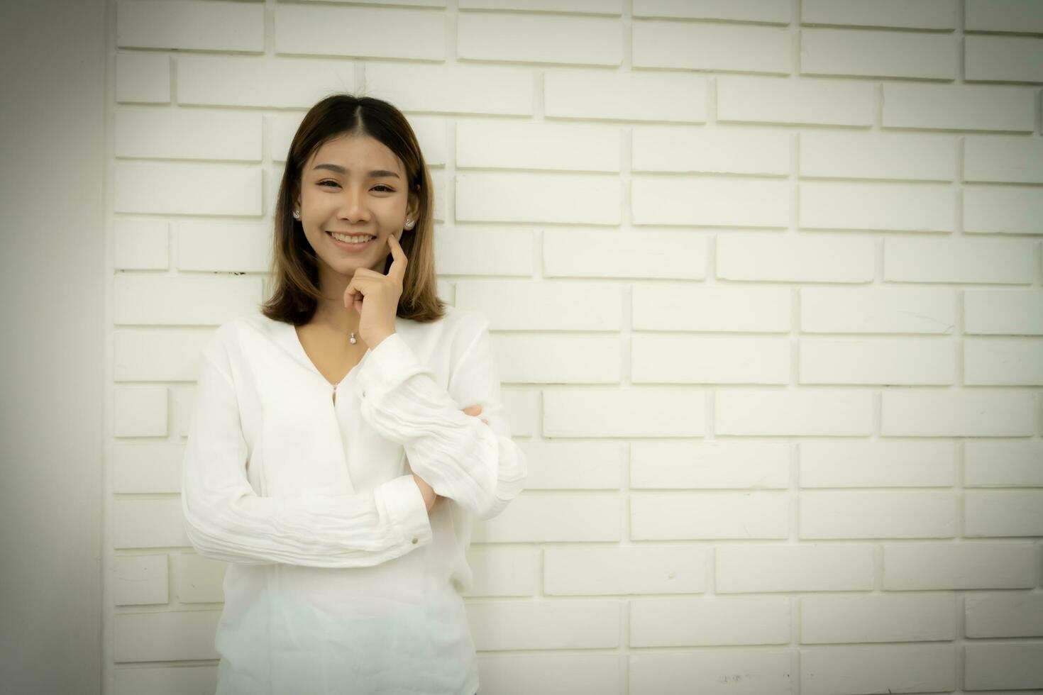 portrait de une magnifique asiatique en ligne vendeur est permanent et en mettant sa doigt sur sa posséder joue avec une sourire sur sa affronter. photo
