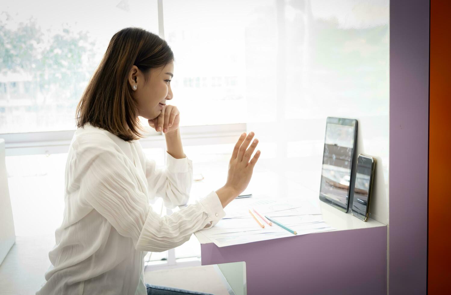 magnifique asiatique en ligne vendeur est salutation le public dans une vivre diffuser tandis que séance dans sa bureau. photo