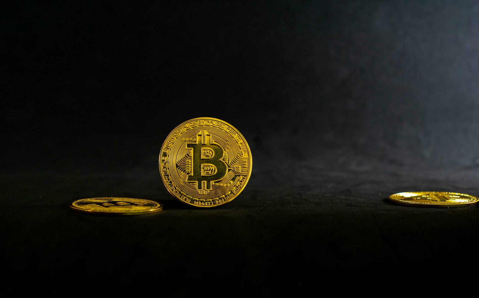 d'or bitcoins, bitcoin allonger sur une noir table avec noir Contexte et rayon de lumière. photo