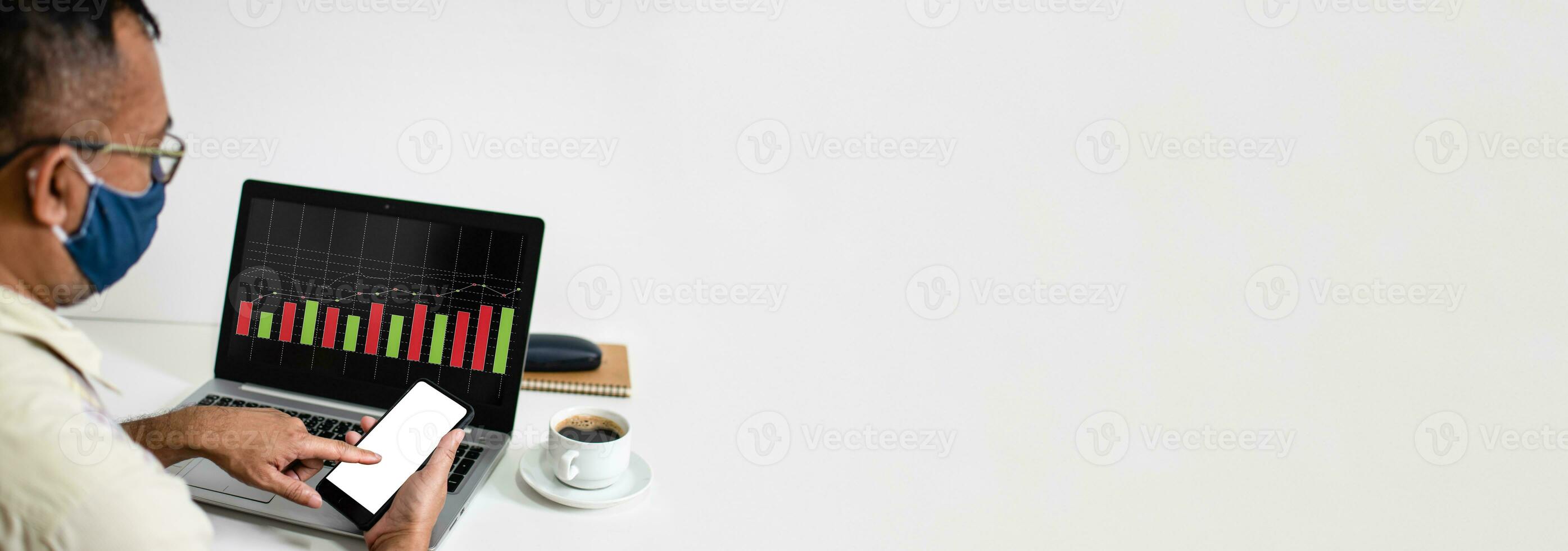 mains de une homme en portant et émouvant une téléphone intelligent avec une Vide blanc écran et portable avec graphique écran sur le bureau blanc dans le travail à Accueil et portant une masque, copie espace, blanc et brouiller Contexte photo