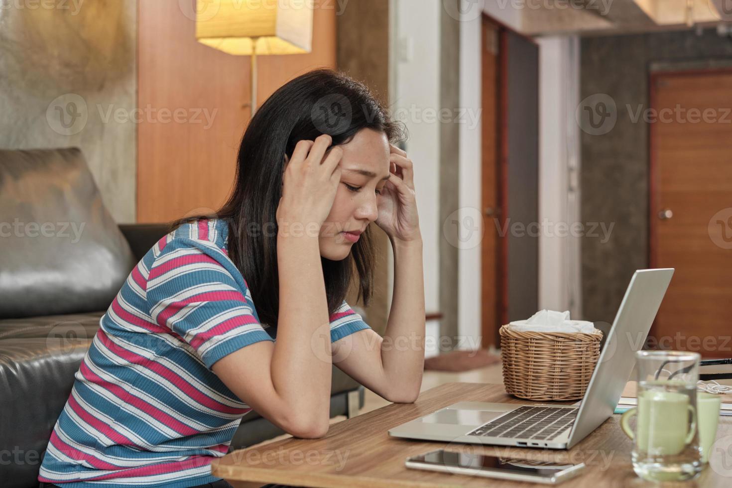 femme asiatique travaillant à la maison est stressée et mal de tête. photo