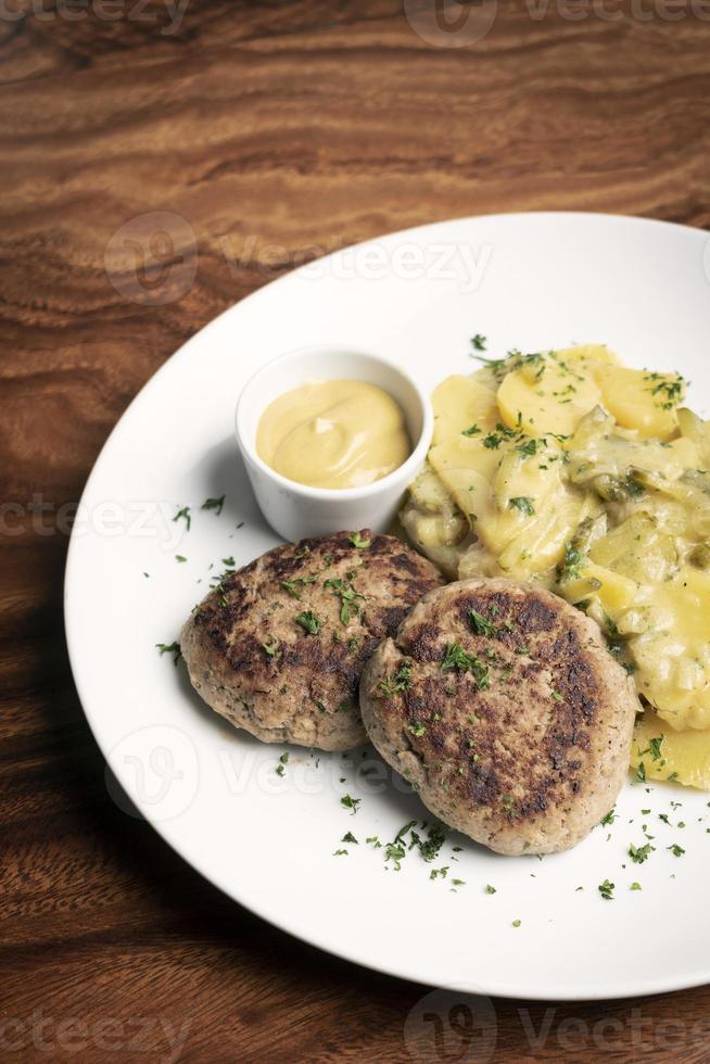 boulettes de viande frikadellen allemandes avec pommes de terre frites crémeuses à l'oignon et sauce moutarde sur fond de table en bois photo