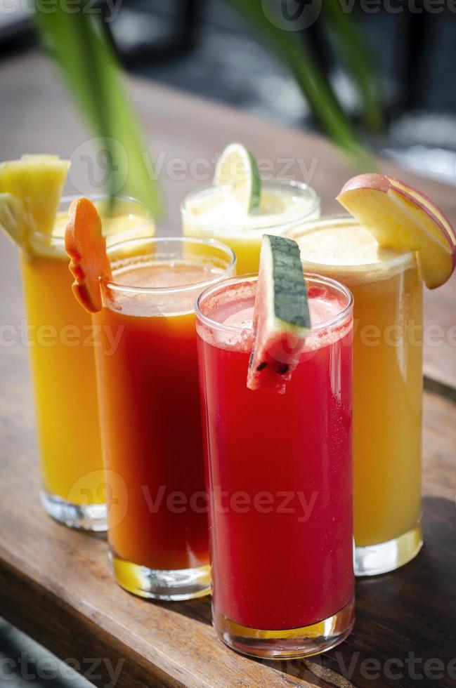 Sélection de verres de jus de fruits biologiques frais mélangés sur une table de jardin ensoleillée photo