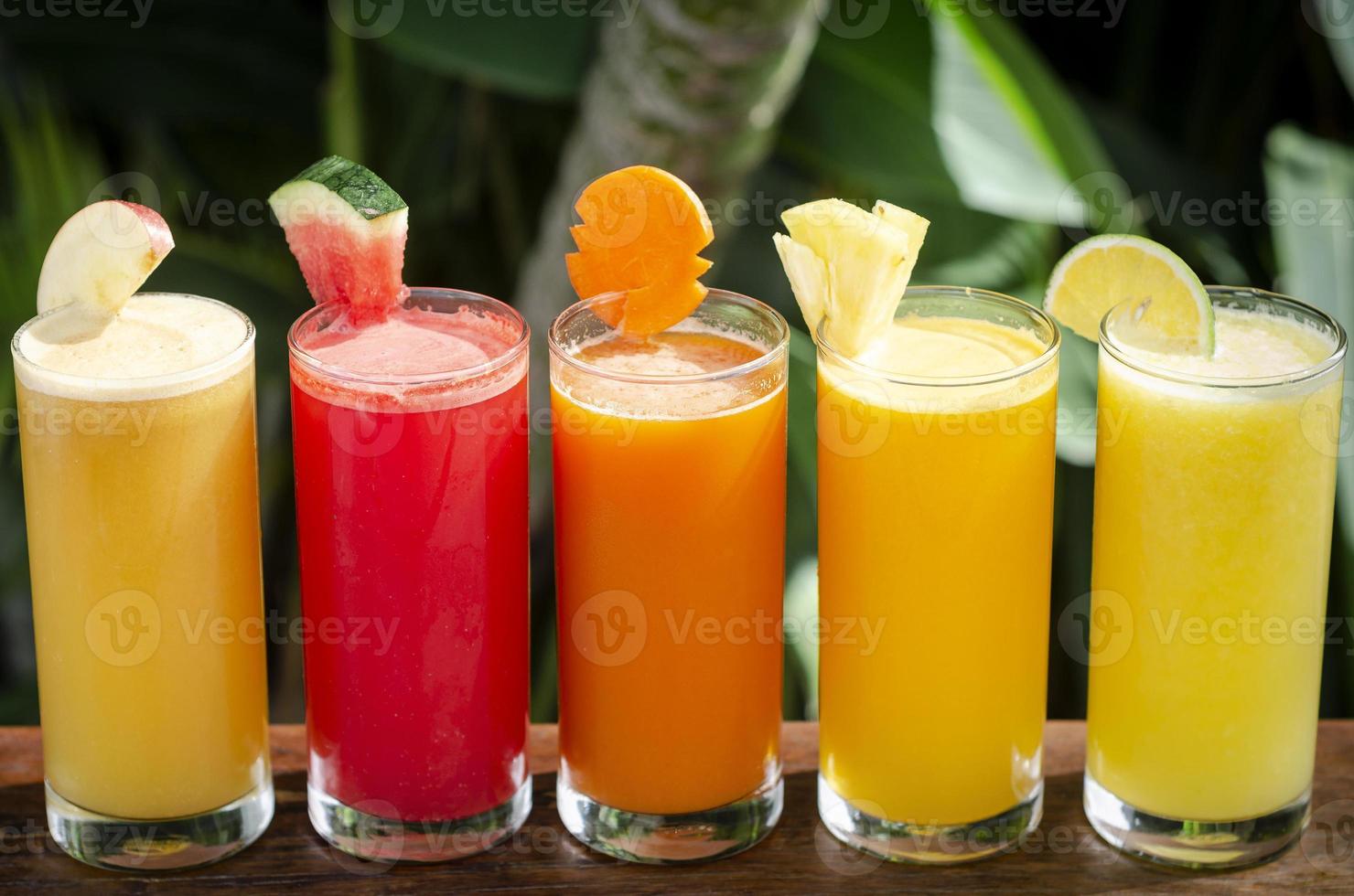 Sélection de verres de jus de fruits biologiques frais mélangés sur une table de jardin ensoleillée photo