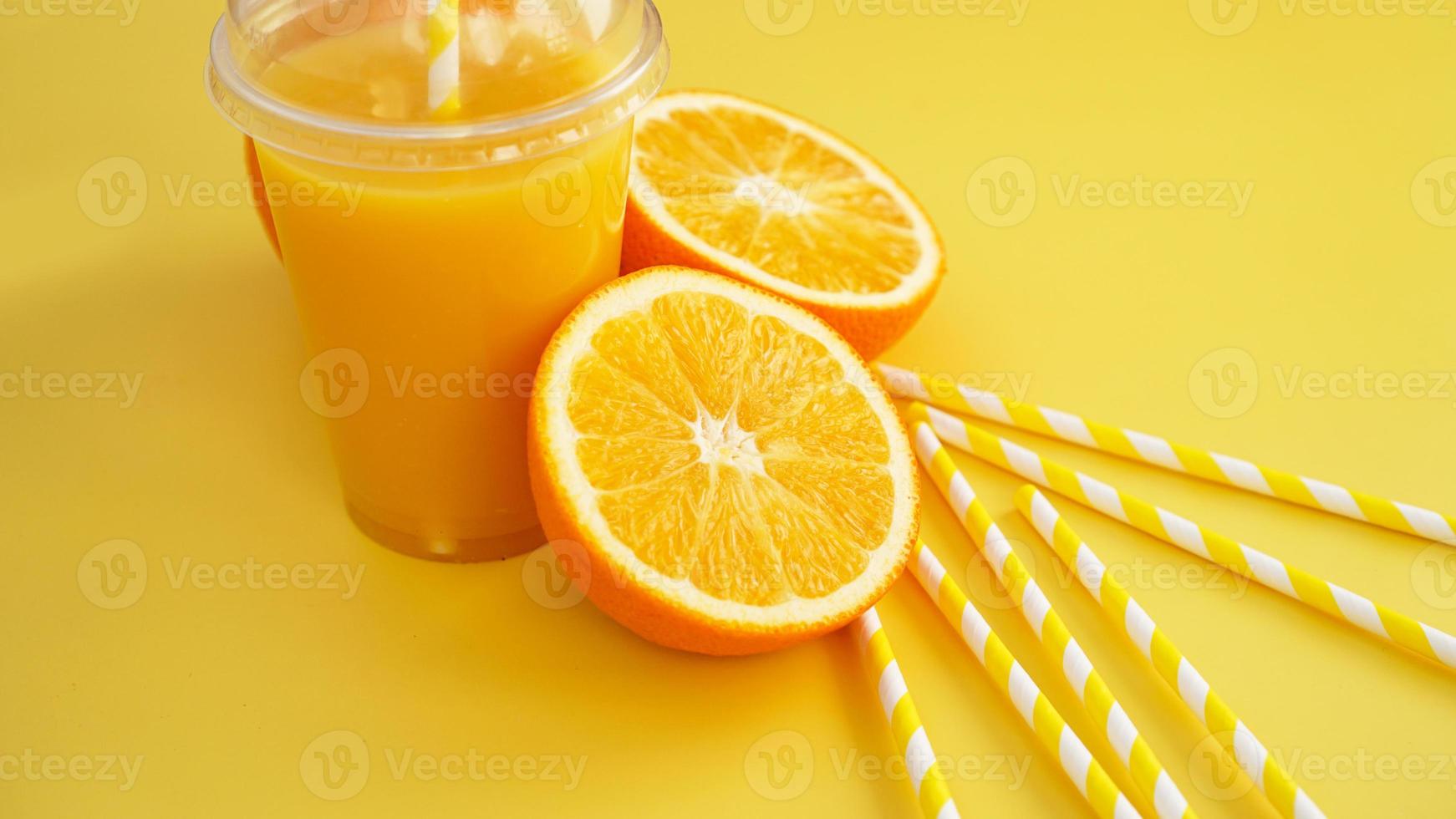 jus d'orange dans une tasse fermée de restauration rapide avec tube sur fond jaune photo