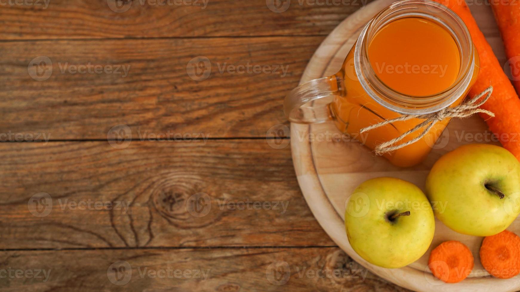 jus de pomme et de carotte en verre, légumes frais et fruits sur bois photo