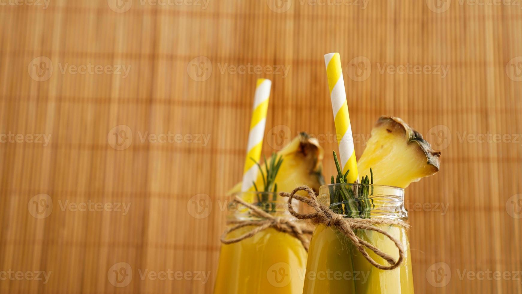 jus d'ananas dans une petite bouteille. des tranches d'ananas décorent la boisson photo