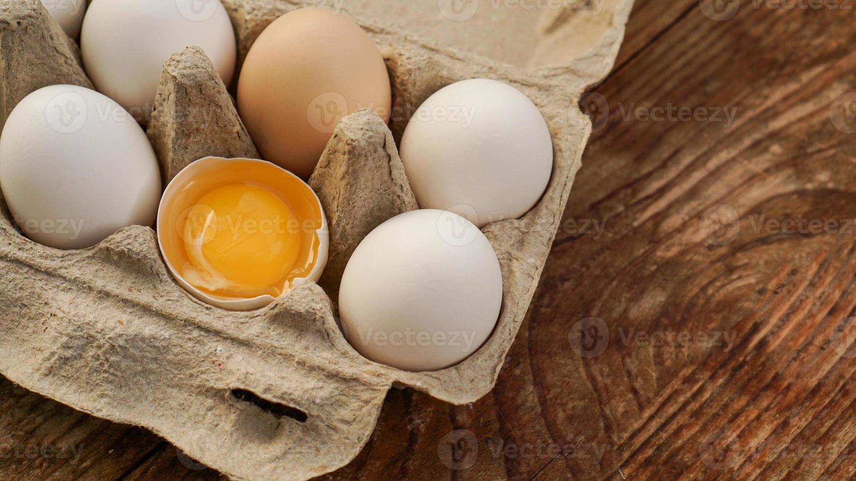 carton d'oeufs blancs et moitié d'oeuf fêlé avec vue de dessus de jaune photo