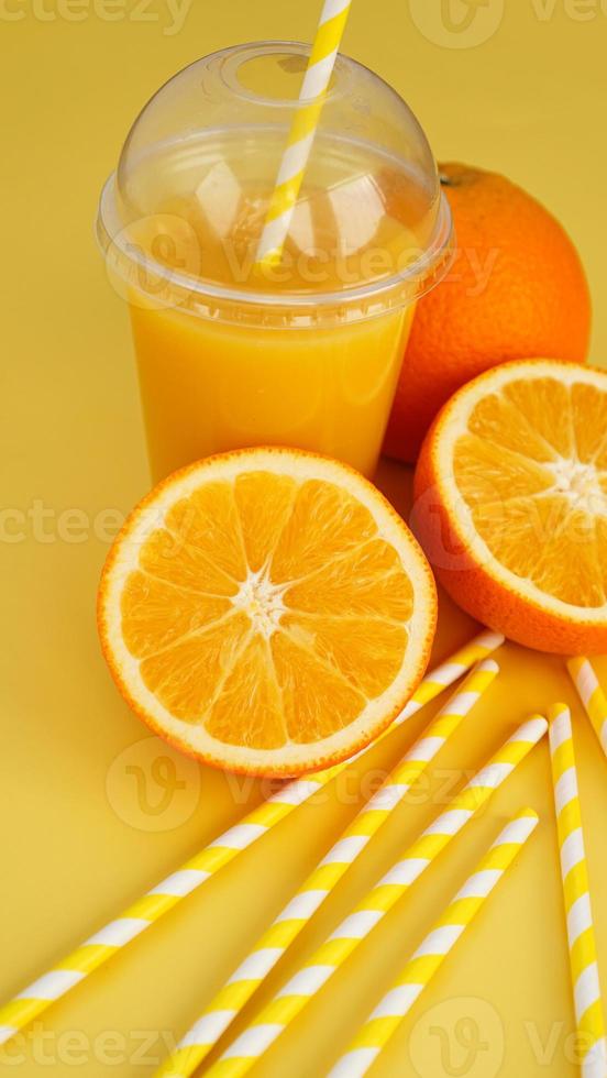 jus d'orange dans une tasse fermée de restauration rapide avec tube sur jaune photo