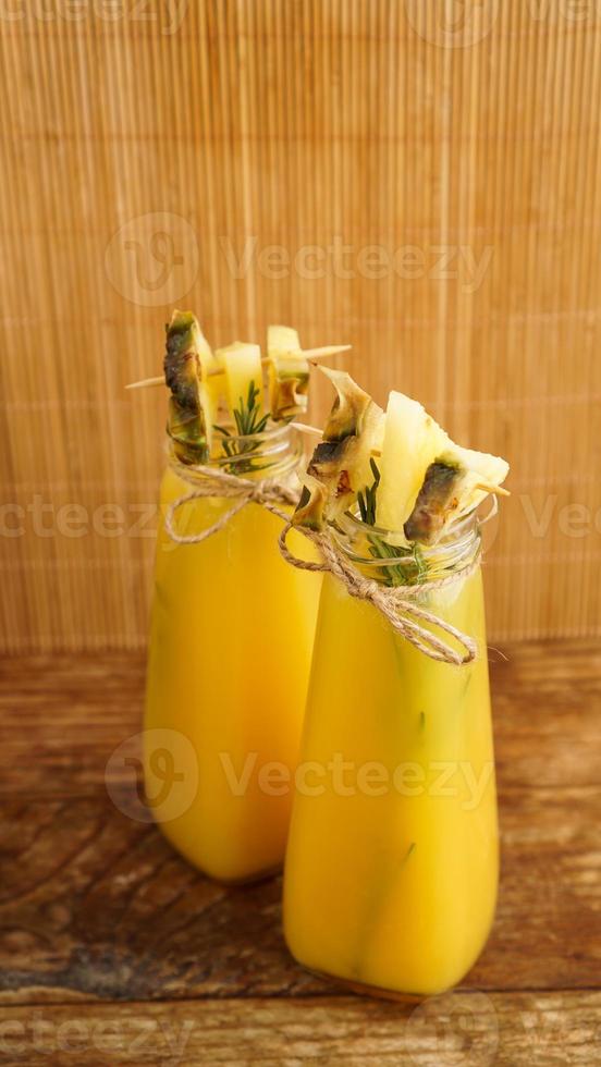 jus d'ananas dans une petite bouteille. des tranches d'ananas décorent la boisson photo