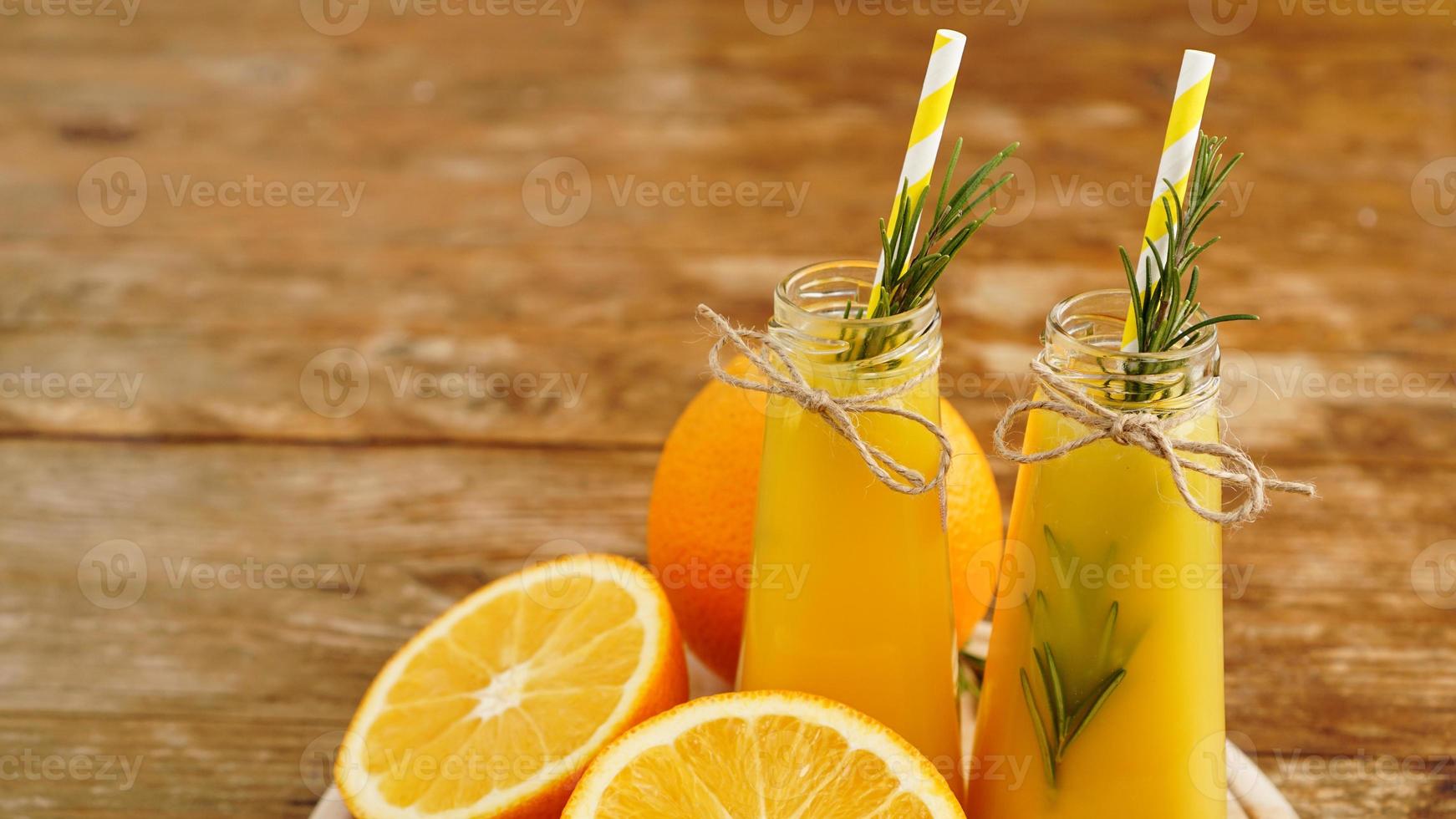 jus d'orange dans des bouteilles en verre. le jus est décoré photo