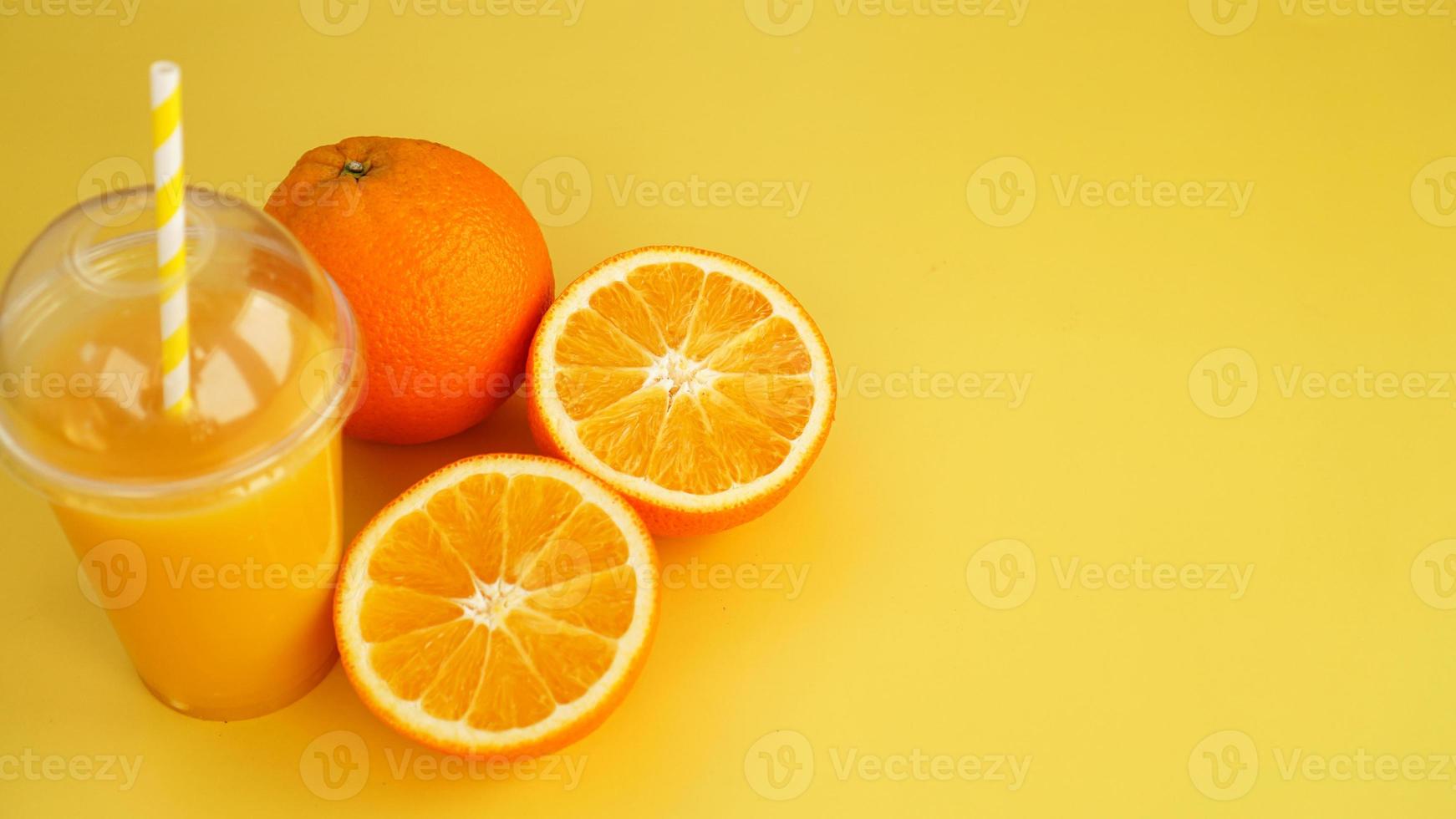 jus d'orange dans un verre en plastique avec une paille. orange en tranches photo