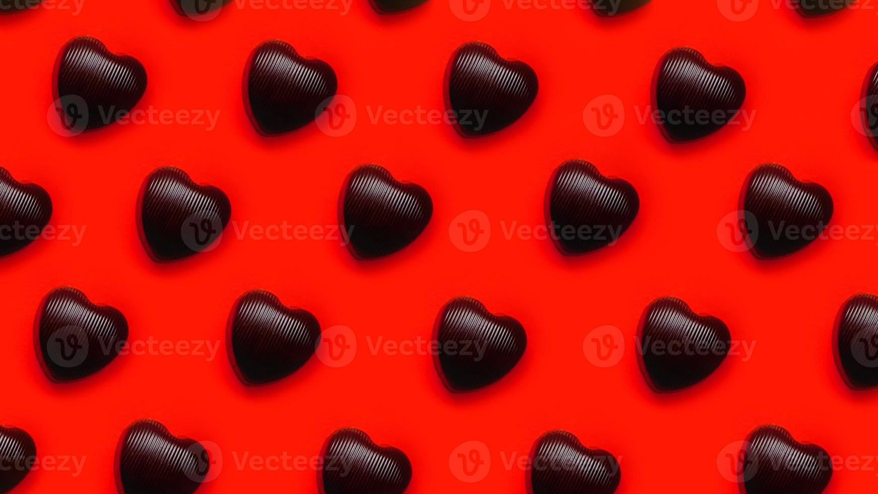 chocolats en forme de coeur au chocolat sur fond rouge d'affilée photo