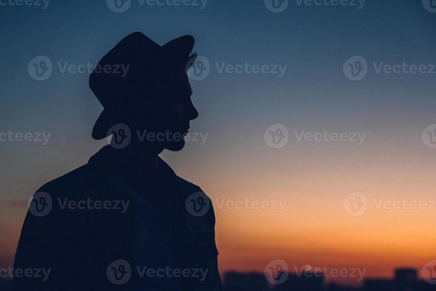 silhouette d'un portrait d'homme, regardant le coucher de soleil sur la ville photo