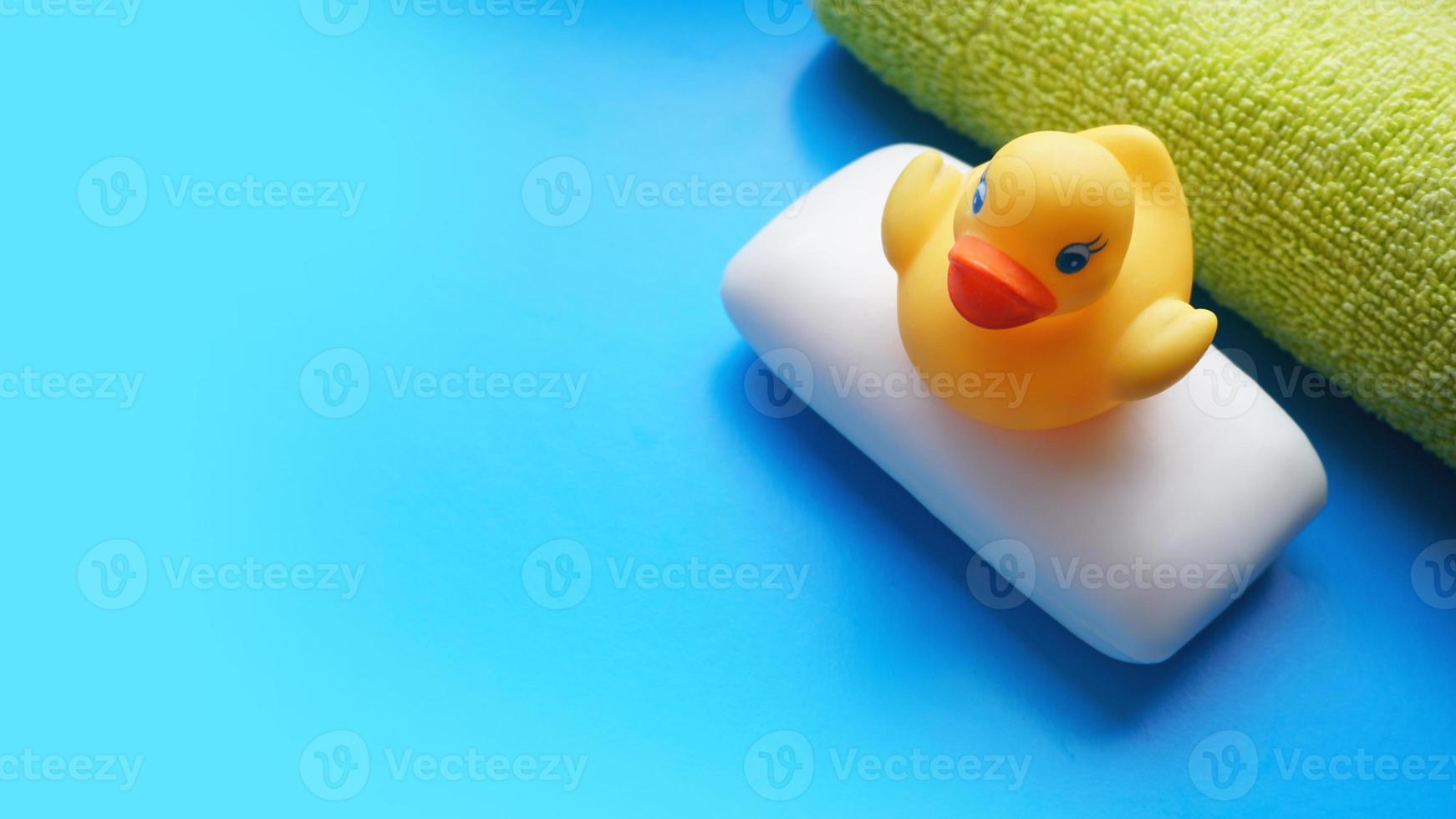 serviette, savon et canard jouet jaune sur fond bleu photo