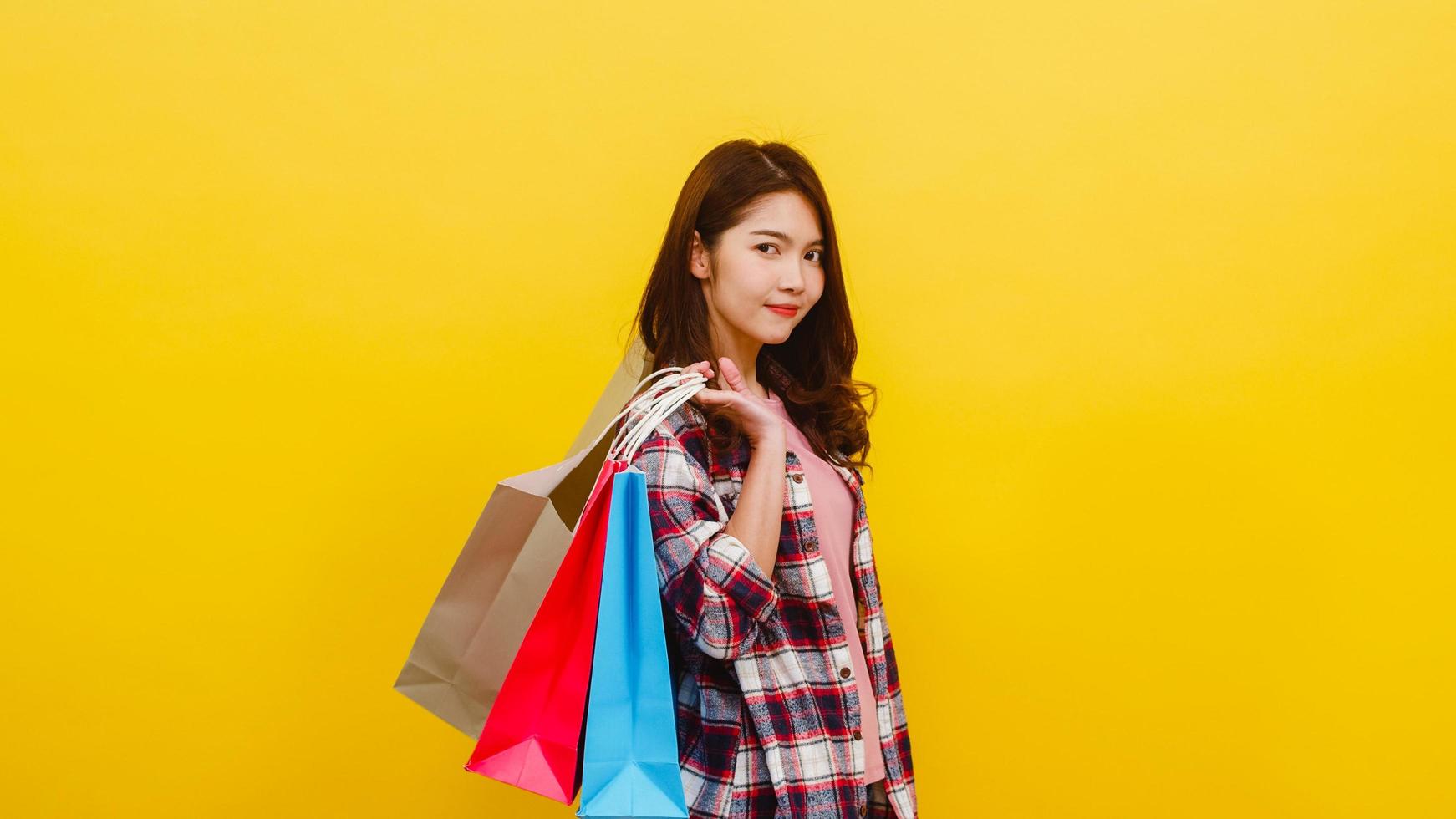 heureuse jeune femme asiatique portant des sacs à provisions avec la main levant. photo