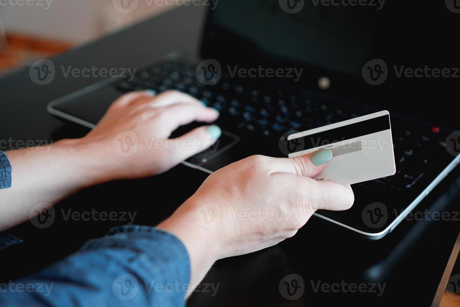 mains tenant une carte de crédit et utilisant un ordinateur portable. shopping en ligne photo