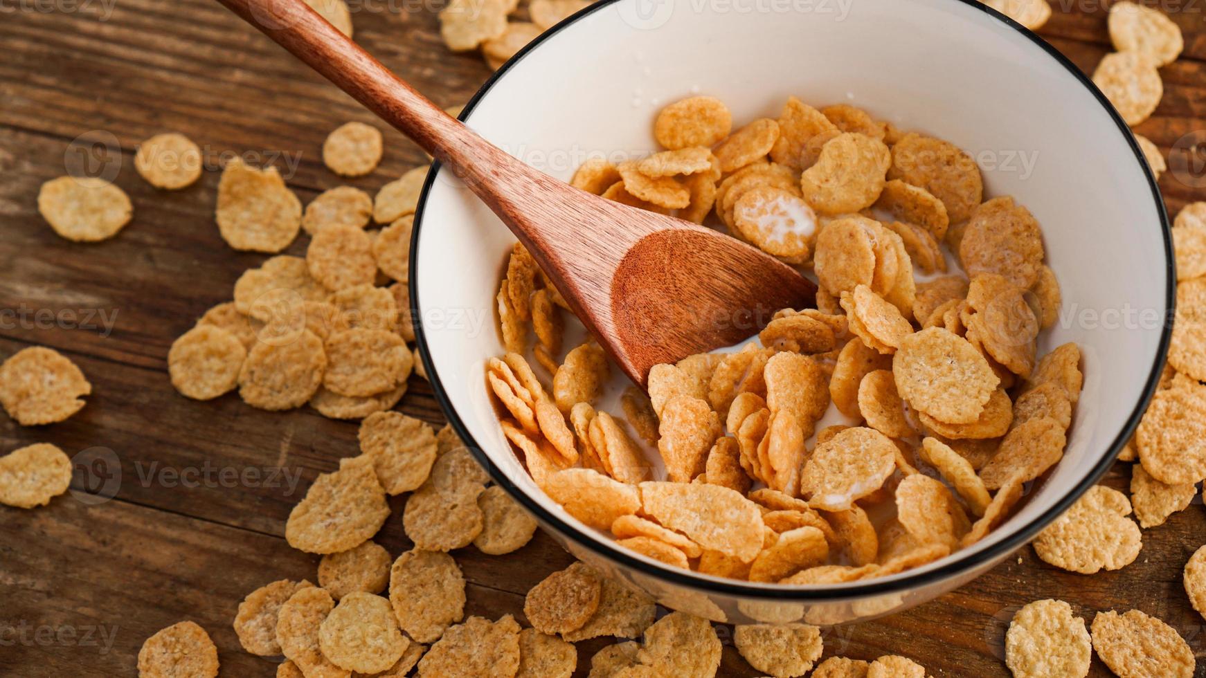 cornflakes jaunes dans un bol blanc. cuillère en bois photo