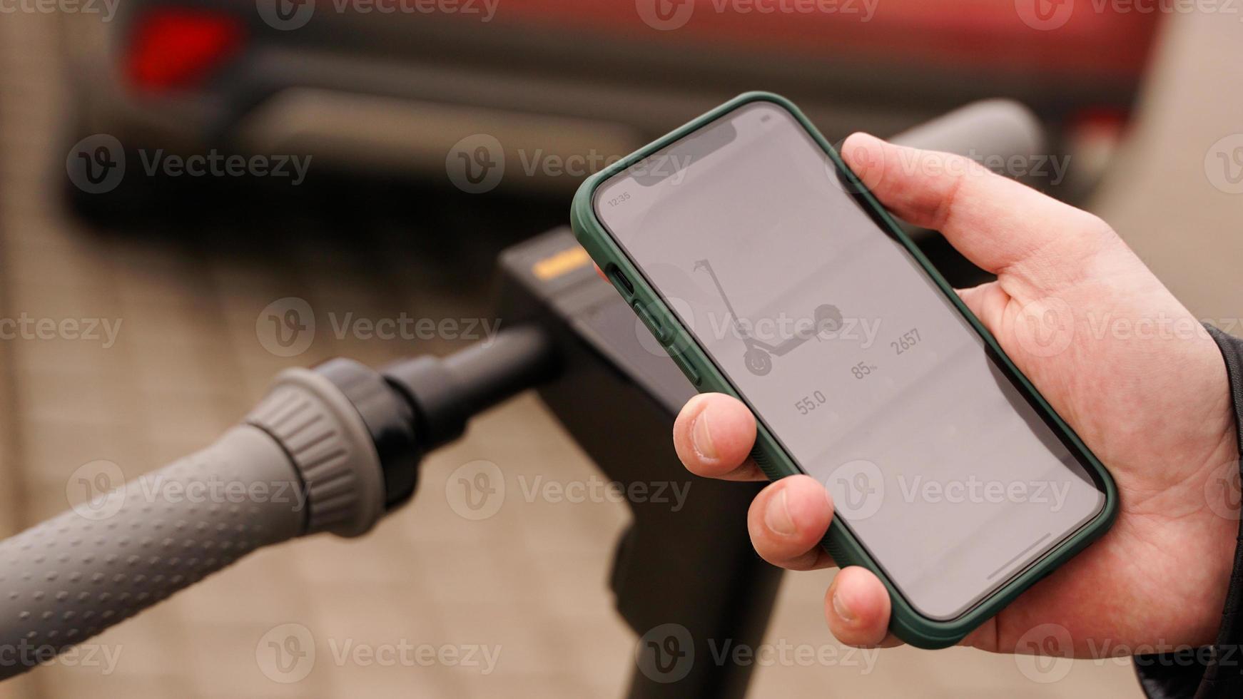 application de scooter électrique. smartphone entre les mains d'un homme. photo