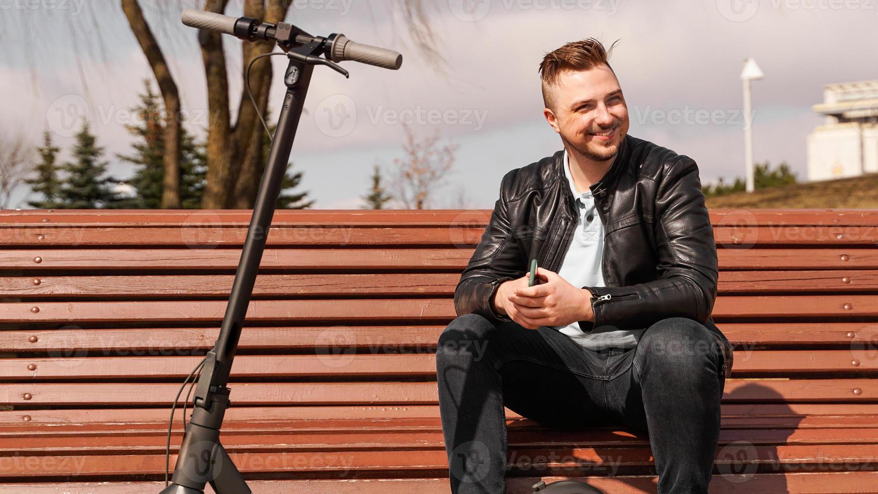 jeune homme est assis sur un banc un jour de printemps. photo