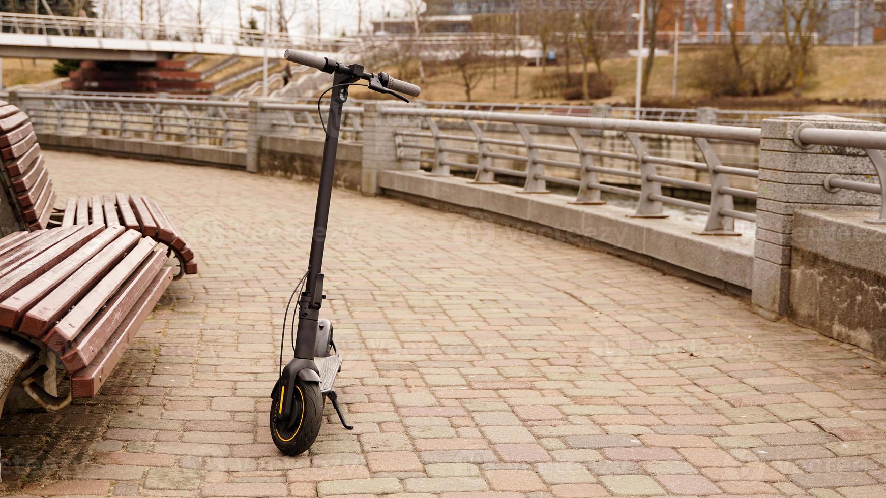 scooter électrique dans le parc à côté du banc. photos sans personnes.