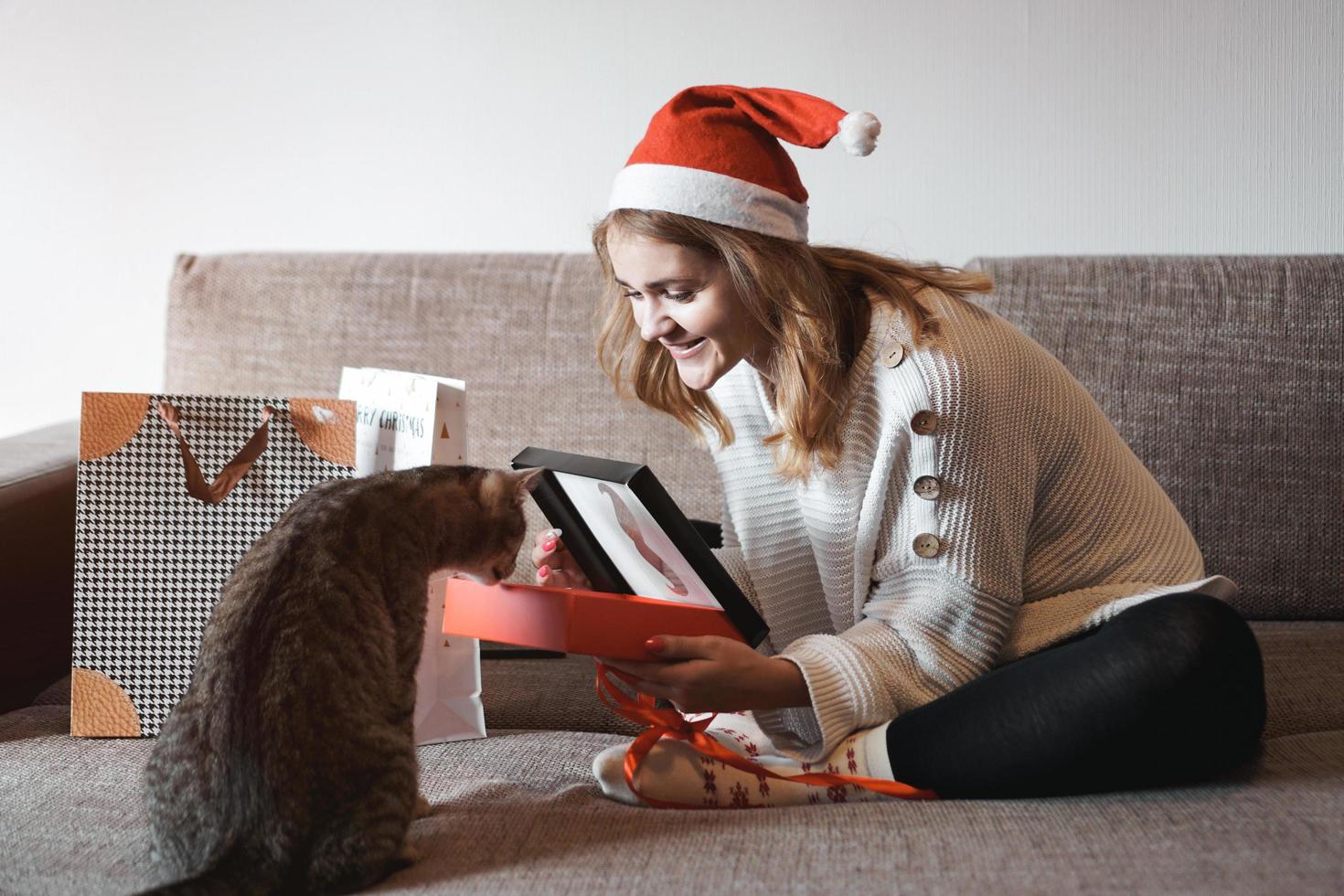 Happy girl in santa hat ouvrant la boîte-cadeau de Noël photo