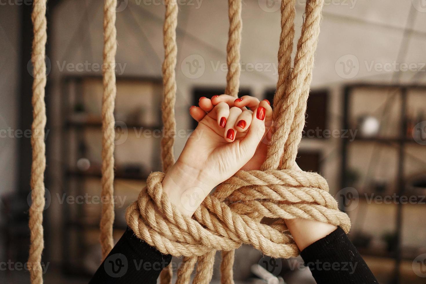 attaché avec une corde mains féminines avec des ongles rouges photo