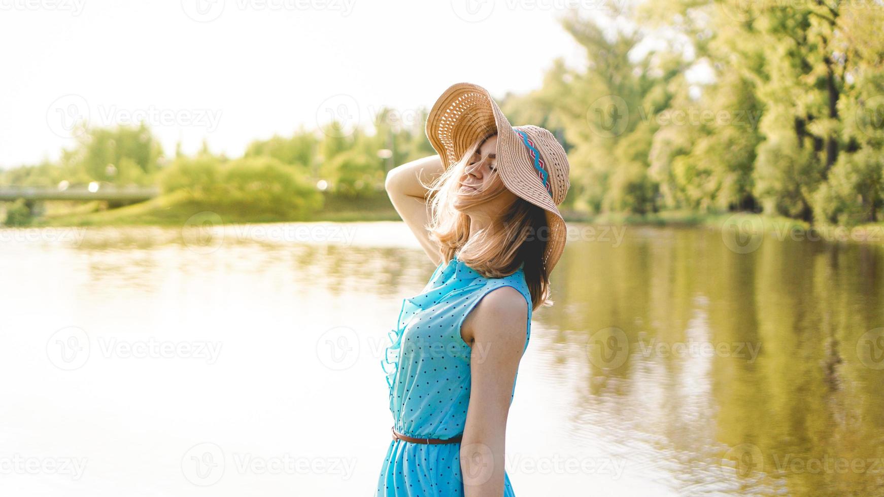 Jeune femme au chapeau de paille dans le jardin ensoleillé photo