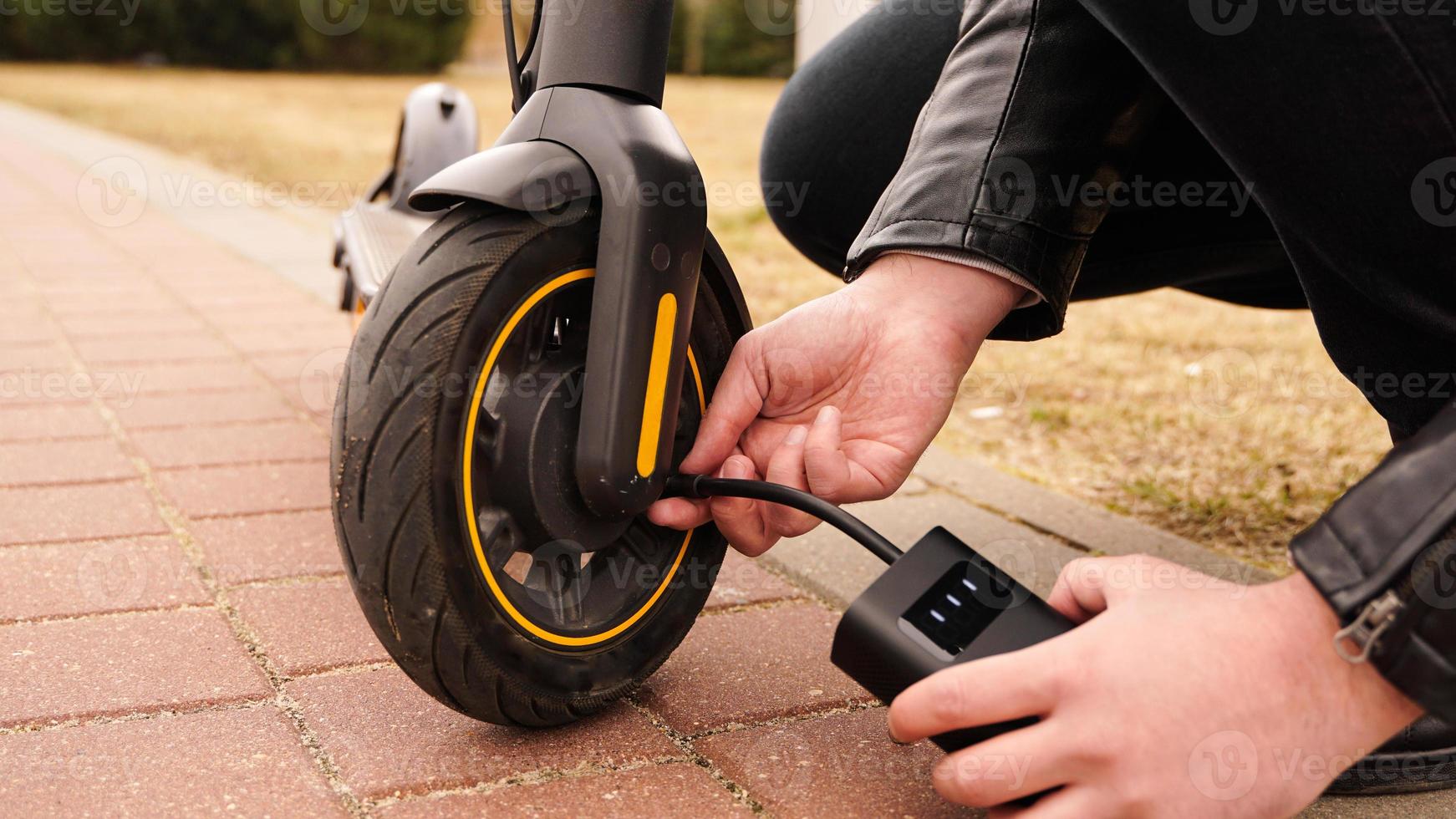 un homme pompe de l'air dans la roue d'un scooter électrique photo