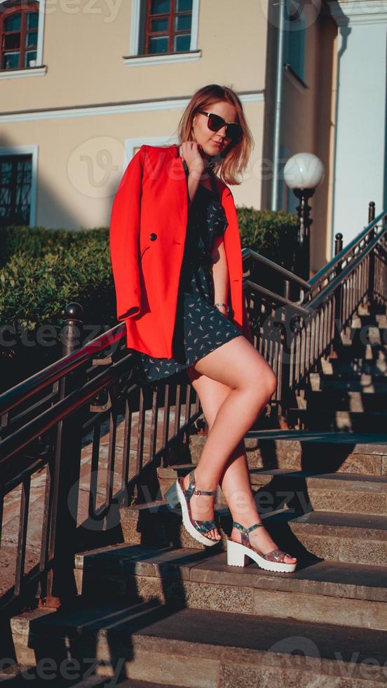 Jolie jeune femme en veste rouge sur fond urbain de la rue de la ville photo