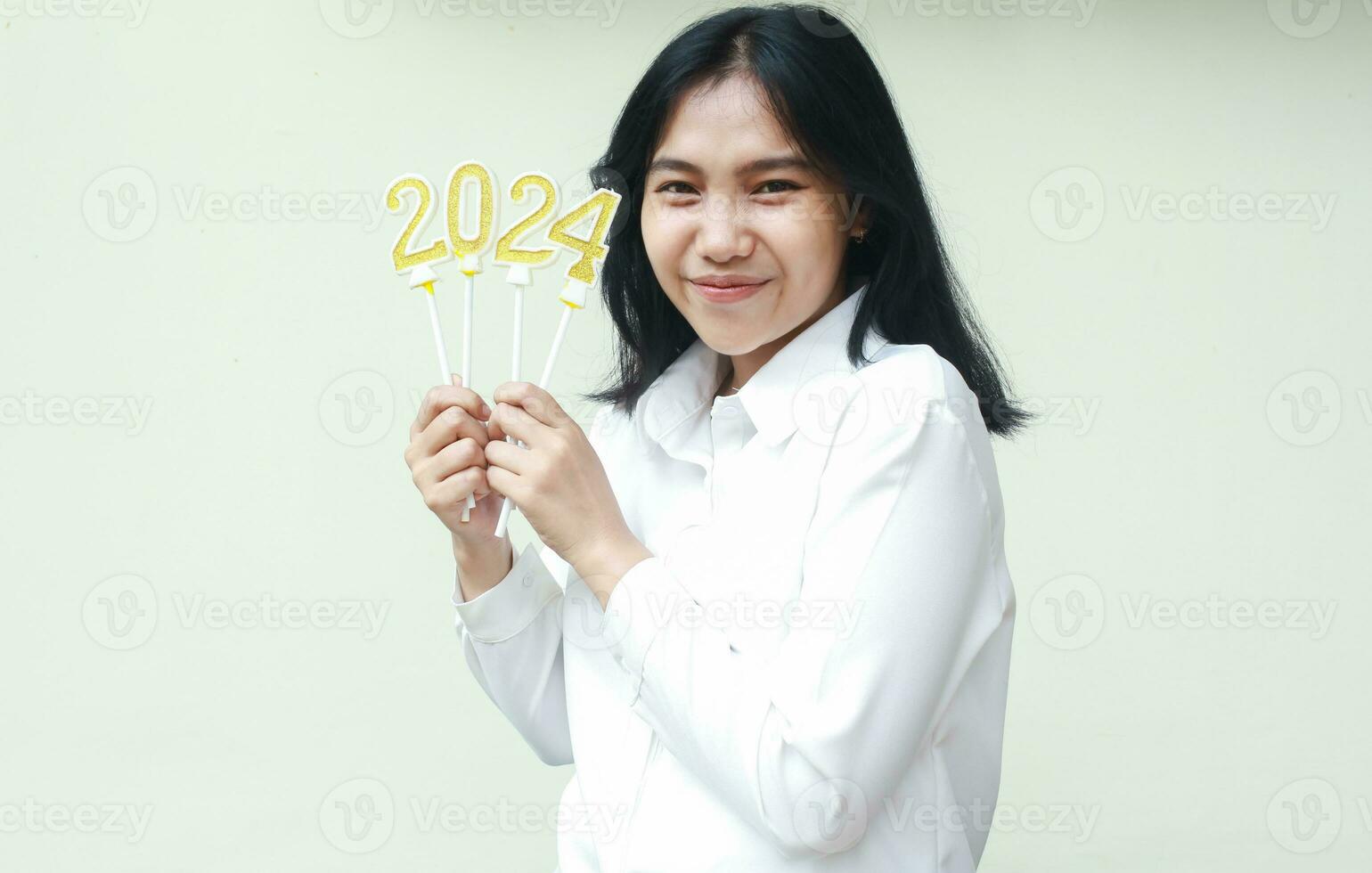 portrait de content asiatique Jeune femme en portant d'or bougies nombre 2024 à célébrer Nouveau ans veille porter formel blanc costume à la recherche à caméra isolé plus de blanc Contexte photo