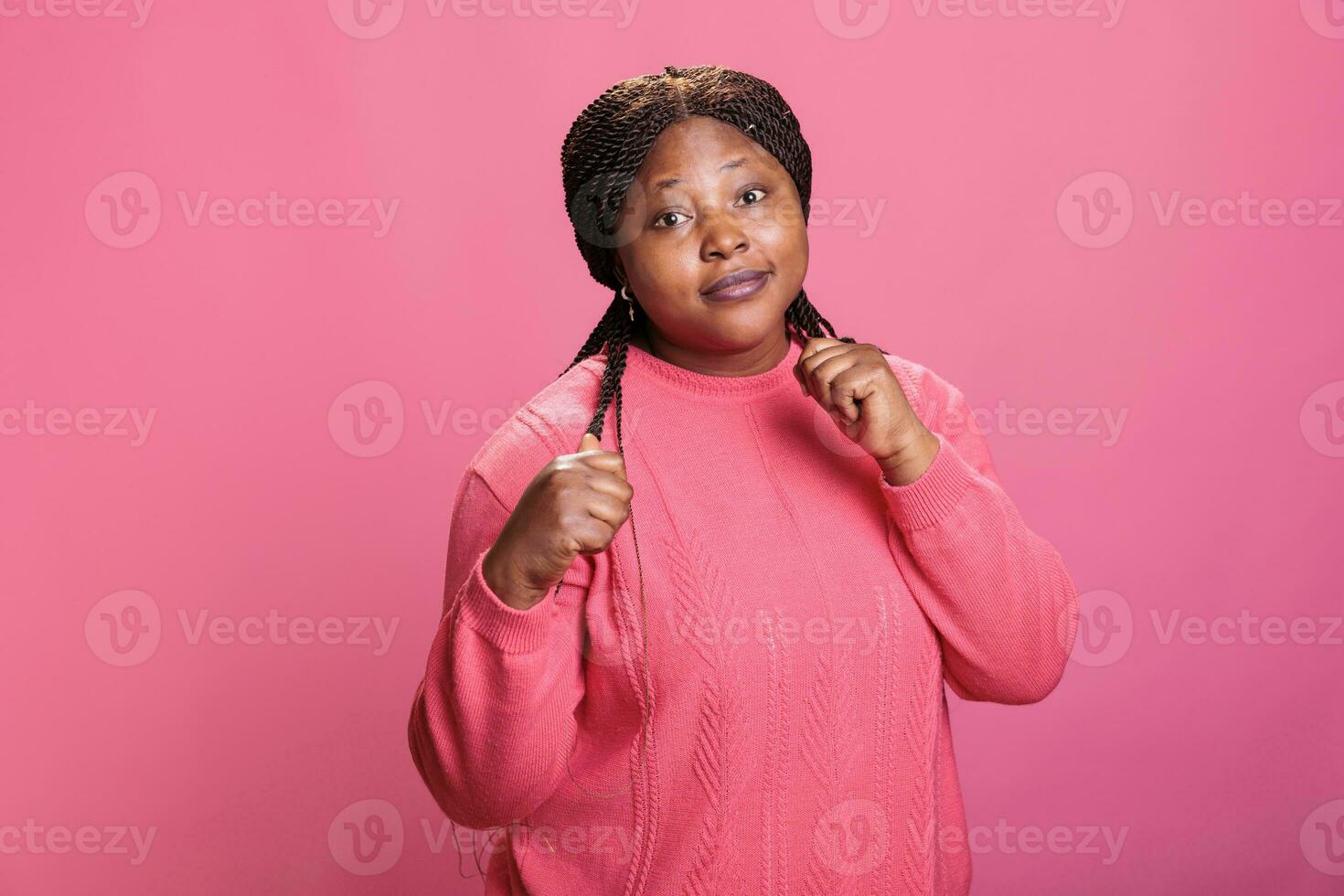 agressif femme serrant les poings et montrant élevé jointures sur caméra dans studio, sentiment en colère et Faire air coups de poing. furieux africain américain adulte en train de préparer à bats toi Faire combat manifestation. photo