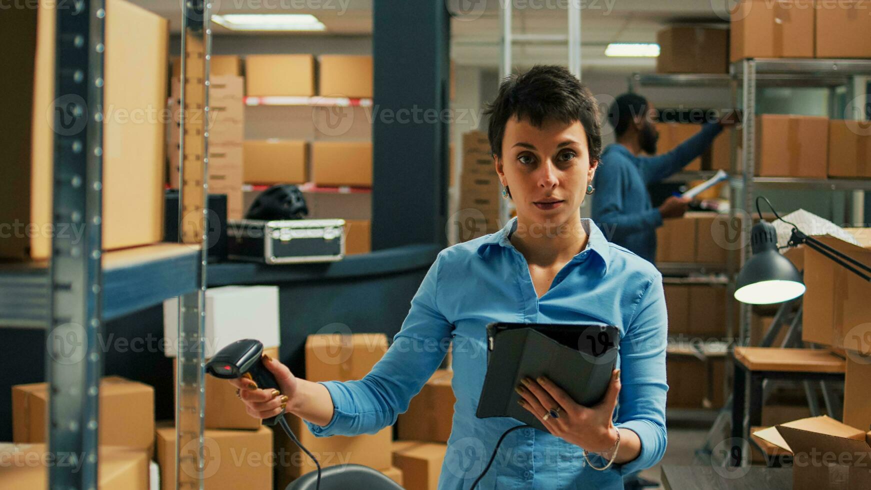 Jeune entrepreneur en utilisant scanner et tablette à faire inventaire, balayage bar code de paquets sur entrepôt étagères. femme vérification Stock de marchandise dans des boites, la fourniture chaîne logistique. photo